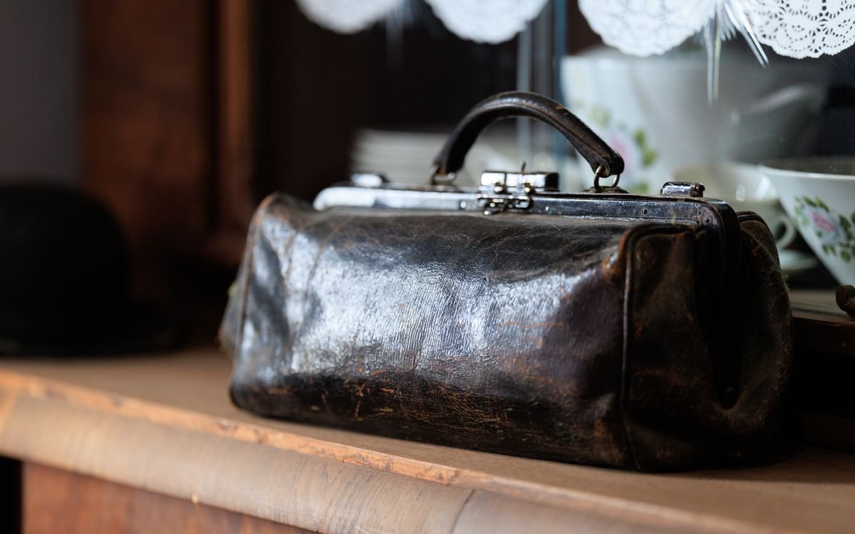 Una borsa in pelle vintage su una mensola di legno, ricca di patina