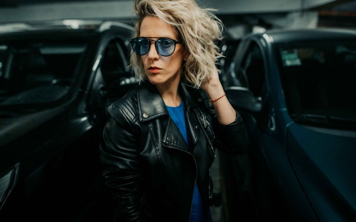 Donna elegante con giacca di pelle, in posa sicura in un contesto urbano