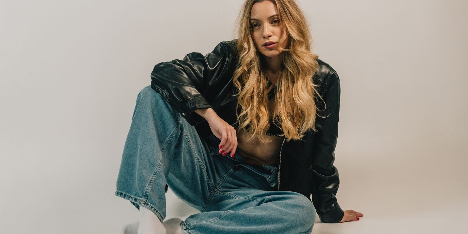 Fashion-forward woman sitting casually in denim and leather jacket