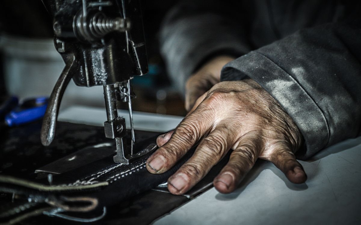 Mani che guidano il materiale sotto una macchina da cucire in laboratorio