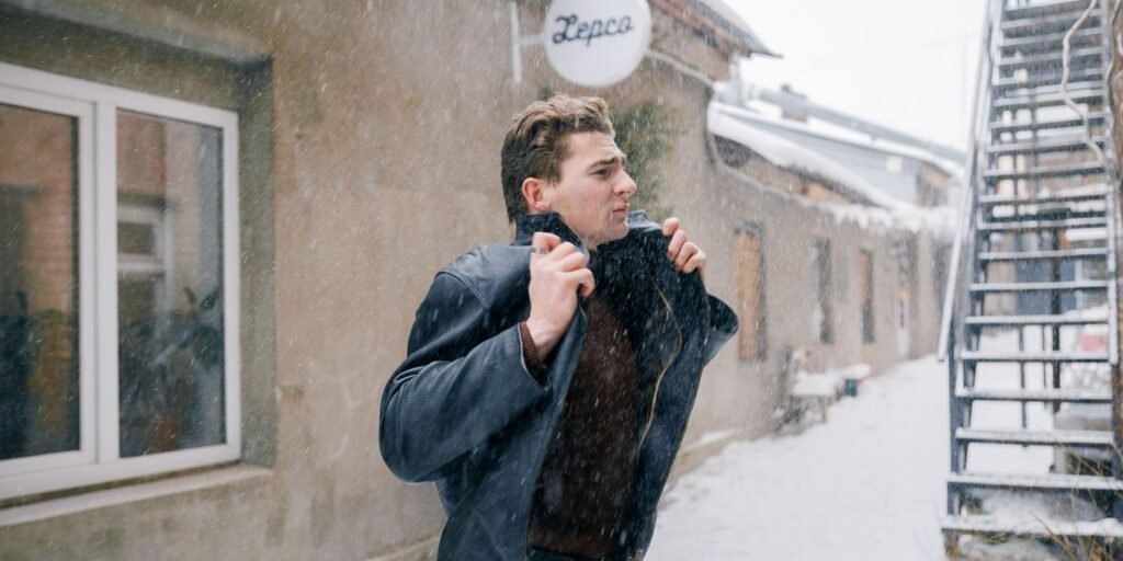 Uomo che cammina all'aperto in inverno tirandosi su il collo contro il freddo