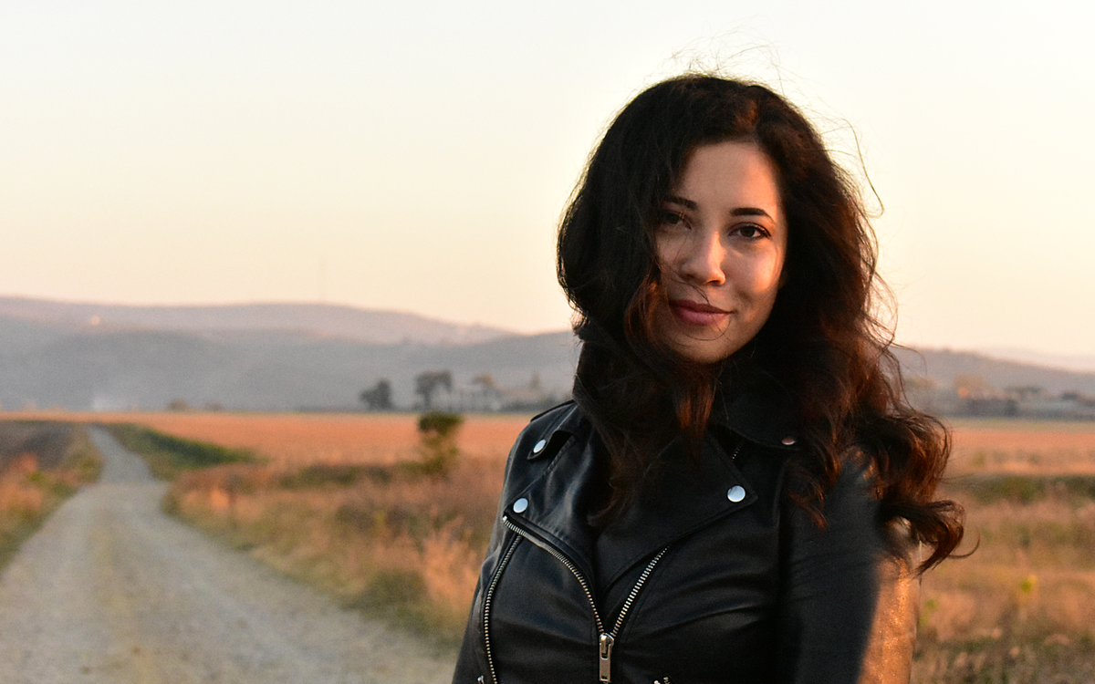 Donna con giacca di pelle nera su una strada di campagna al tramonto