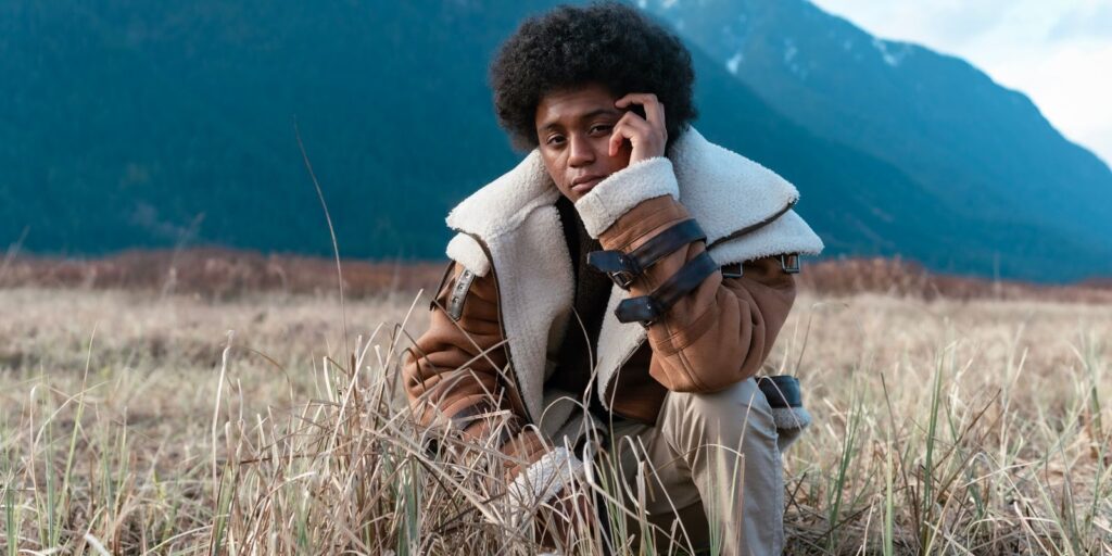 Un uomo con una giacca di pelle dal collo in shearling in un paesaggio di montagna