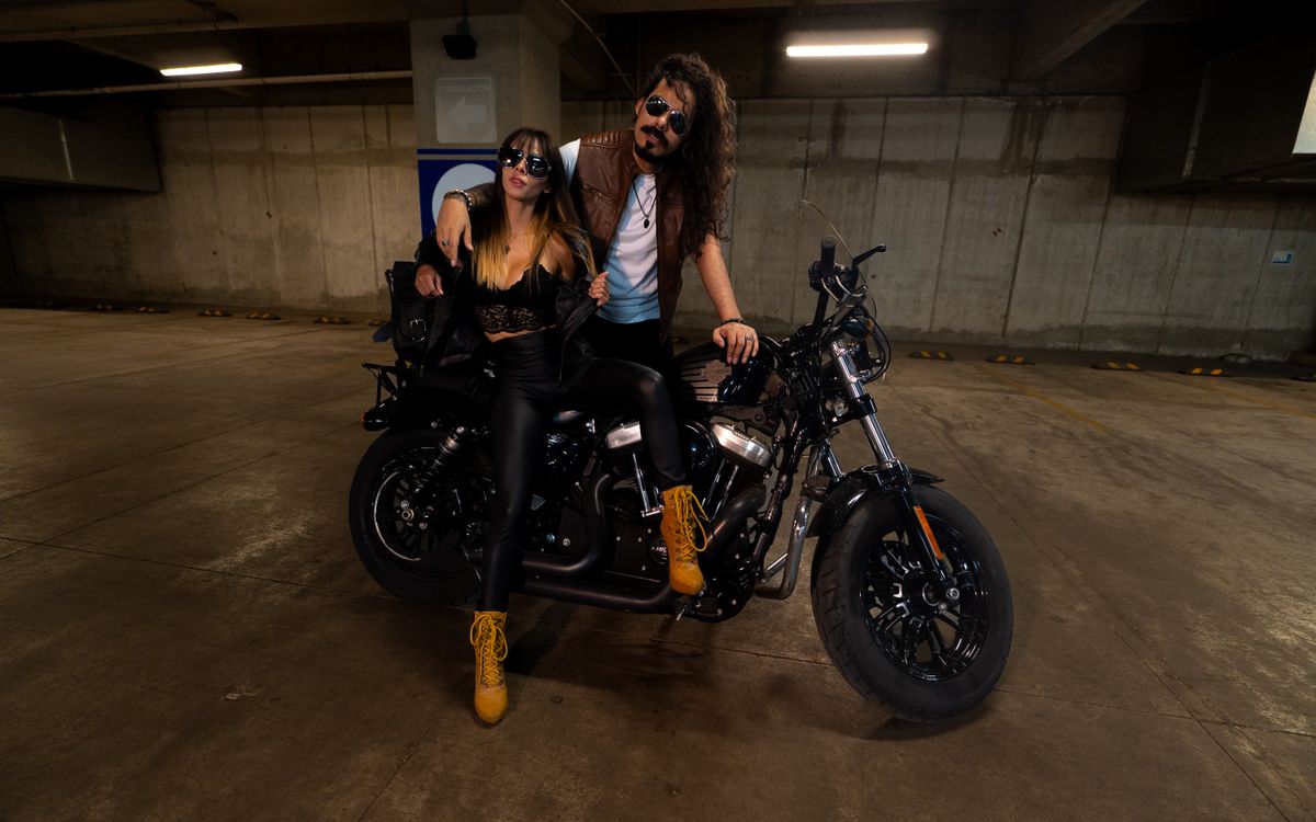 Coppia elegante in outfit di pelle in posa accanto a una moto in un garage
