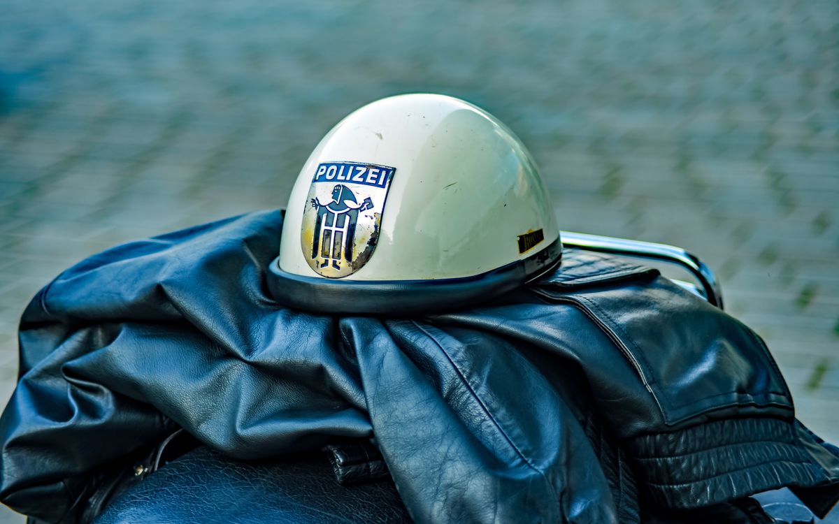 Un casco della polizia vintage con distintivo appoggiato su una giacca di pelle all'aperto