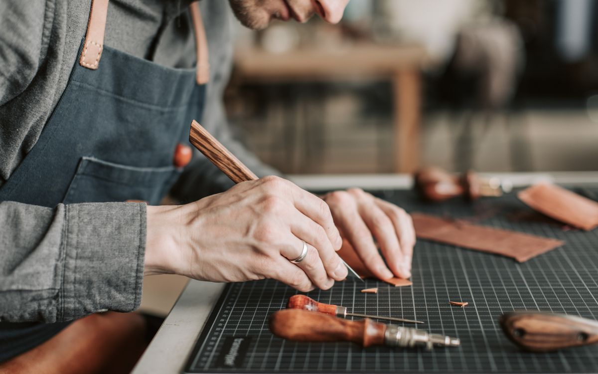 Primo piano di un artigiano che lavora la pelle a mano in un laboratorio