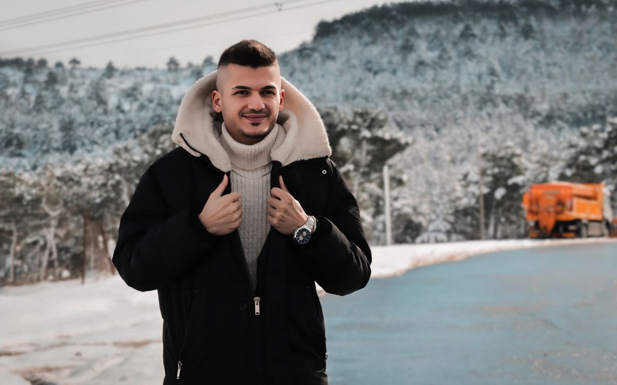 Un giovane uomo in abbigliamento invernale davanti a una foresta innevata