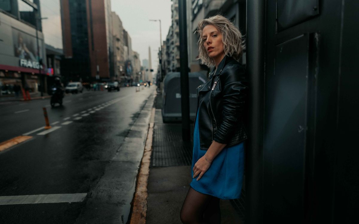 Donna elegante con giacca di pelle in una strada di città sotto la pioggia