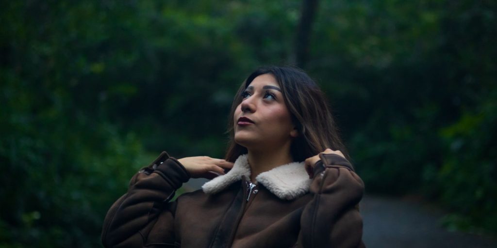 Donna con una calda giacca di pelle marrone su un sentiero nel bosco