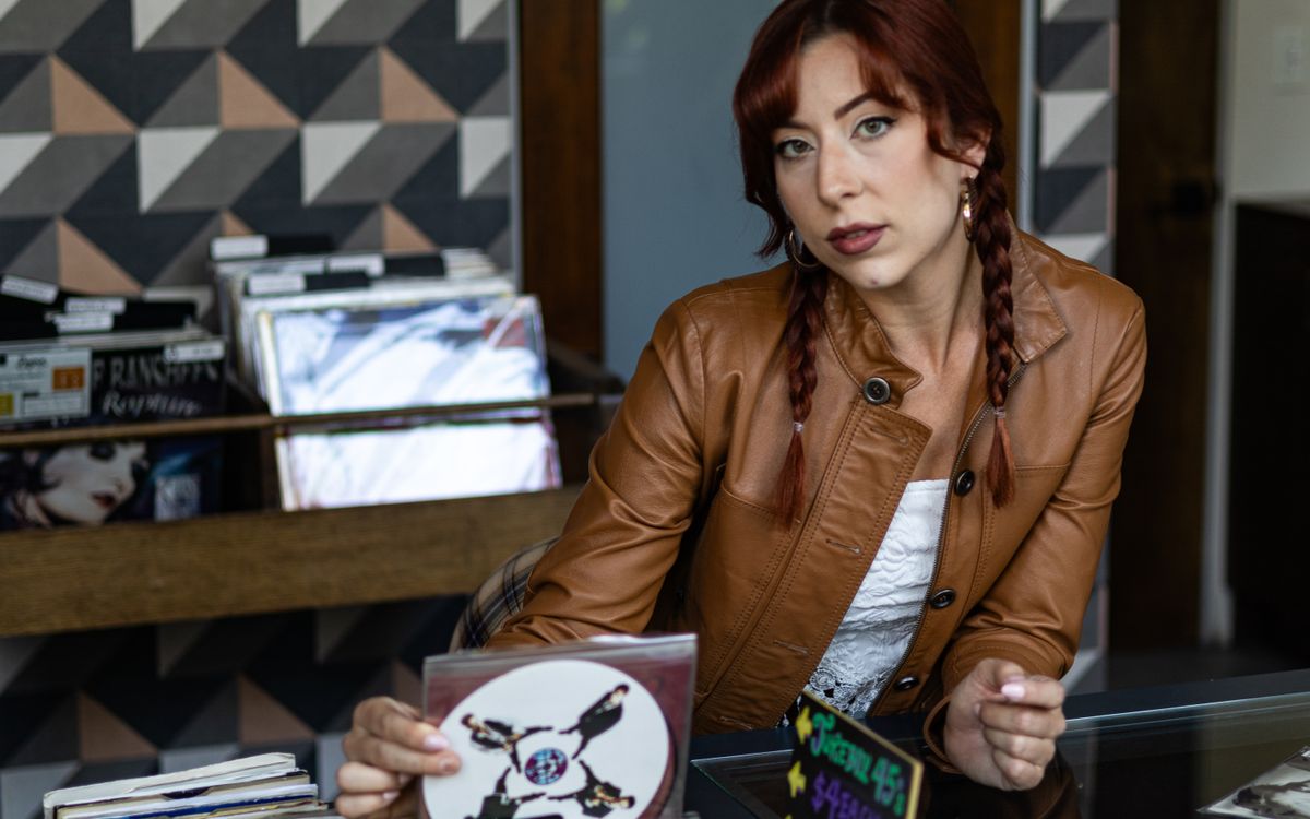 Donna in giacca di pelle mentre sfoglia dei vinili in un negozio vintage