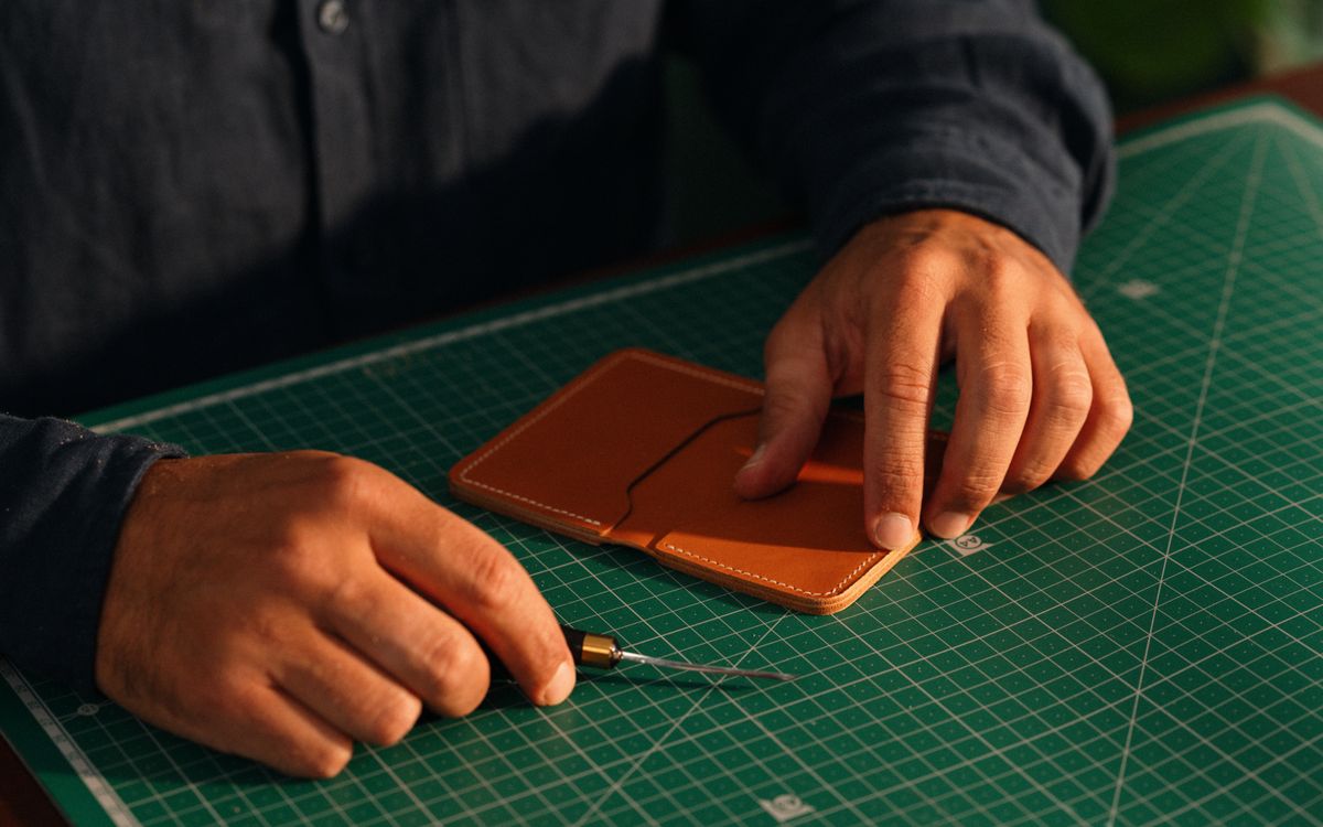 Primo piano di mani che modellano un pezzo di pelle sul banco da lavoro