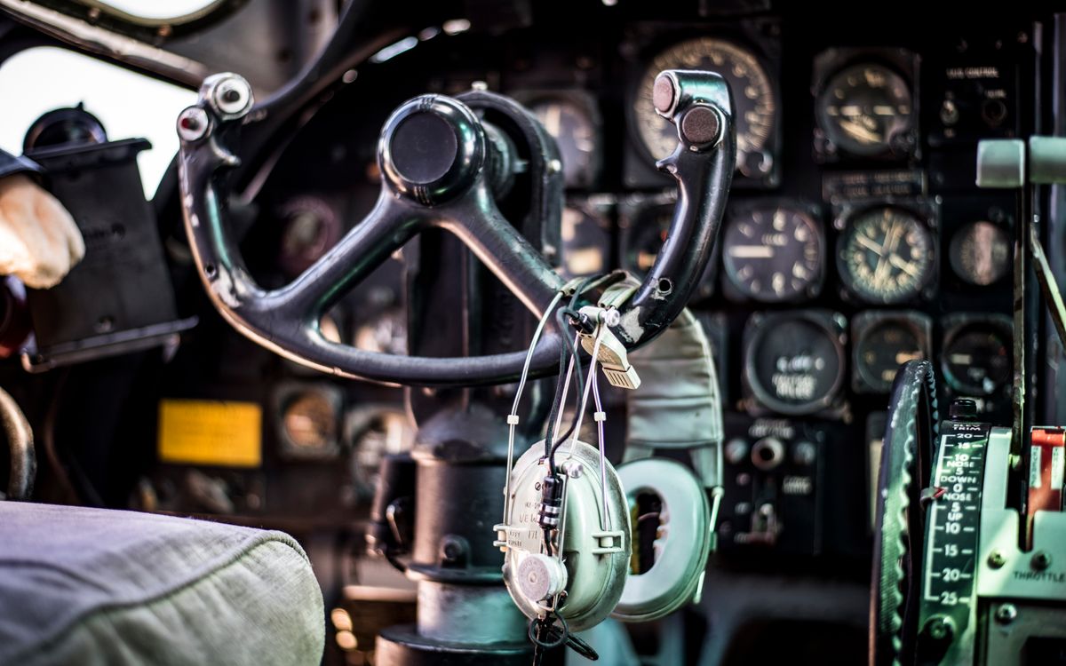 Primo piano della cabina di pilotaggio di un vecchio aereo con comandi, strumenti e cuffie